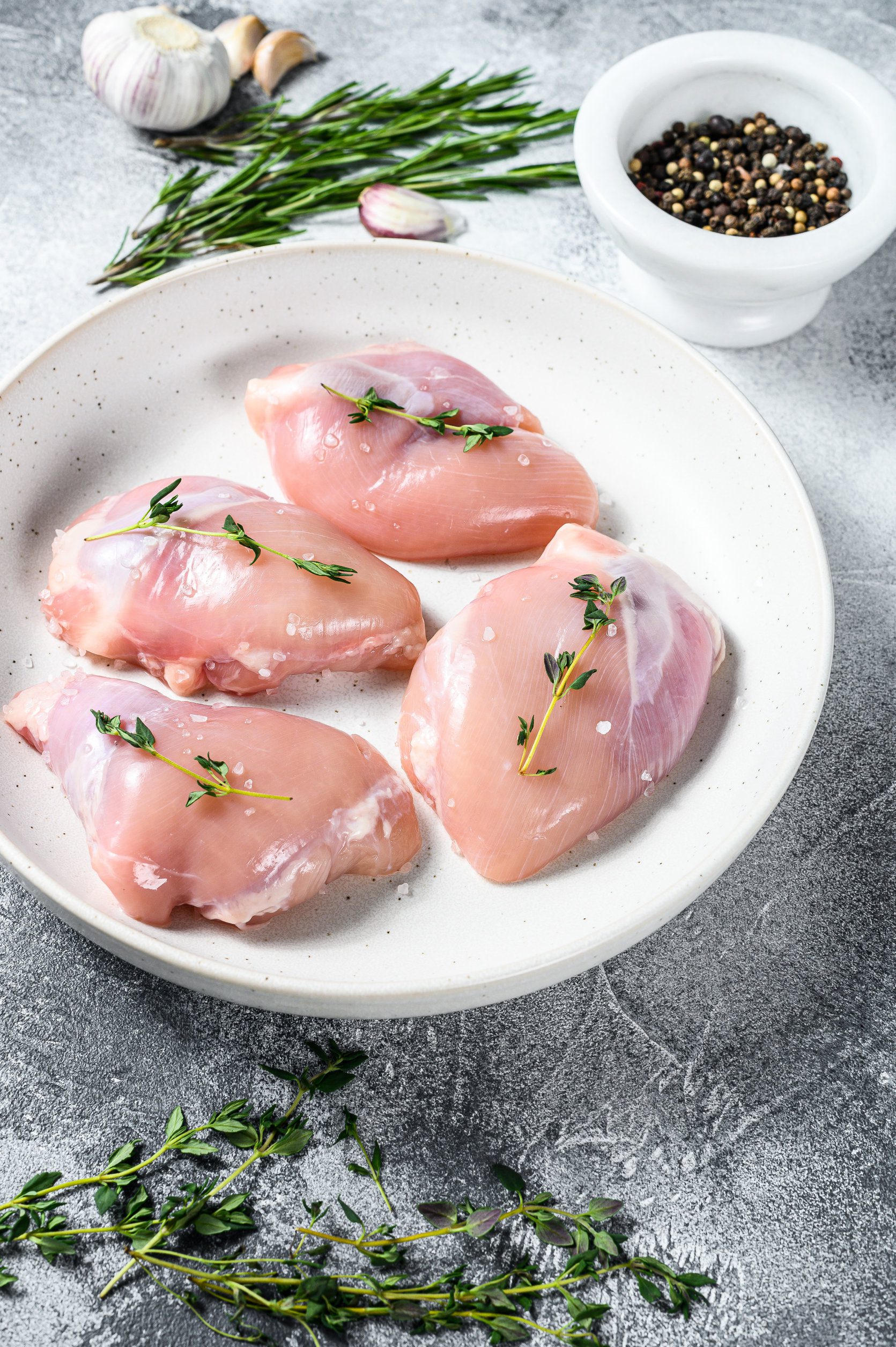 Raw chicken thigh fillet. Gray background. Top view Raw chicken thigh fillet. Gray background. Top view.